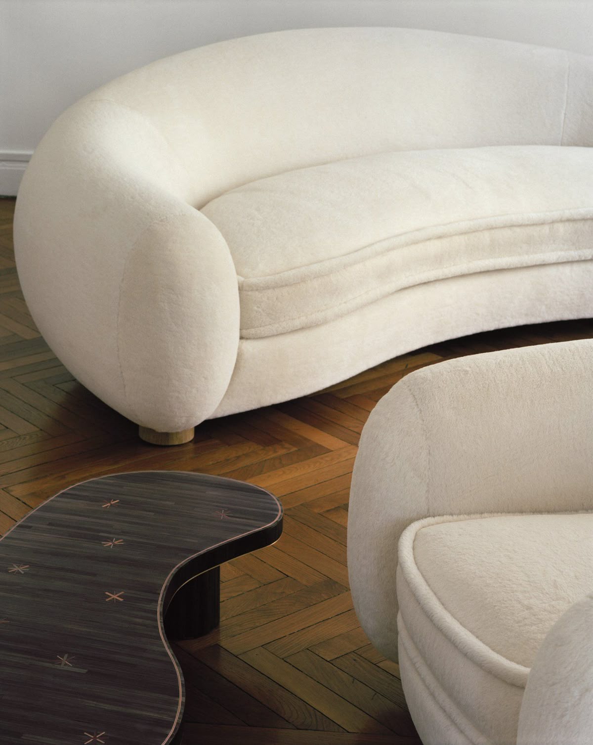 Curved bouclé sofa on herringbone parquet